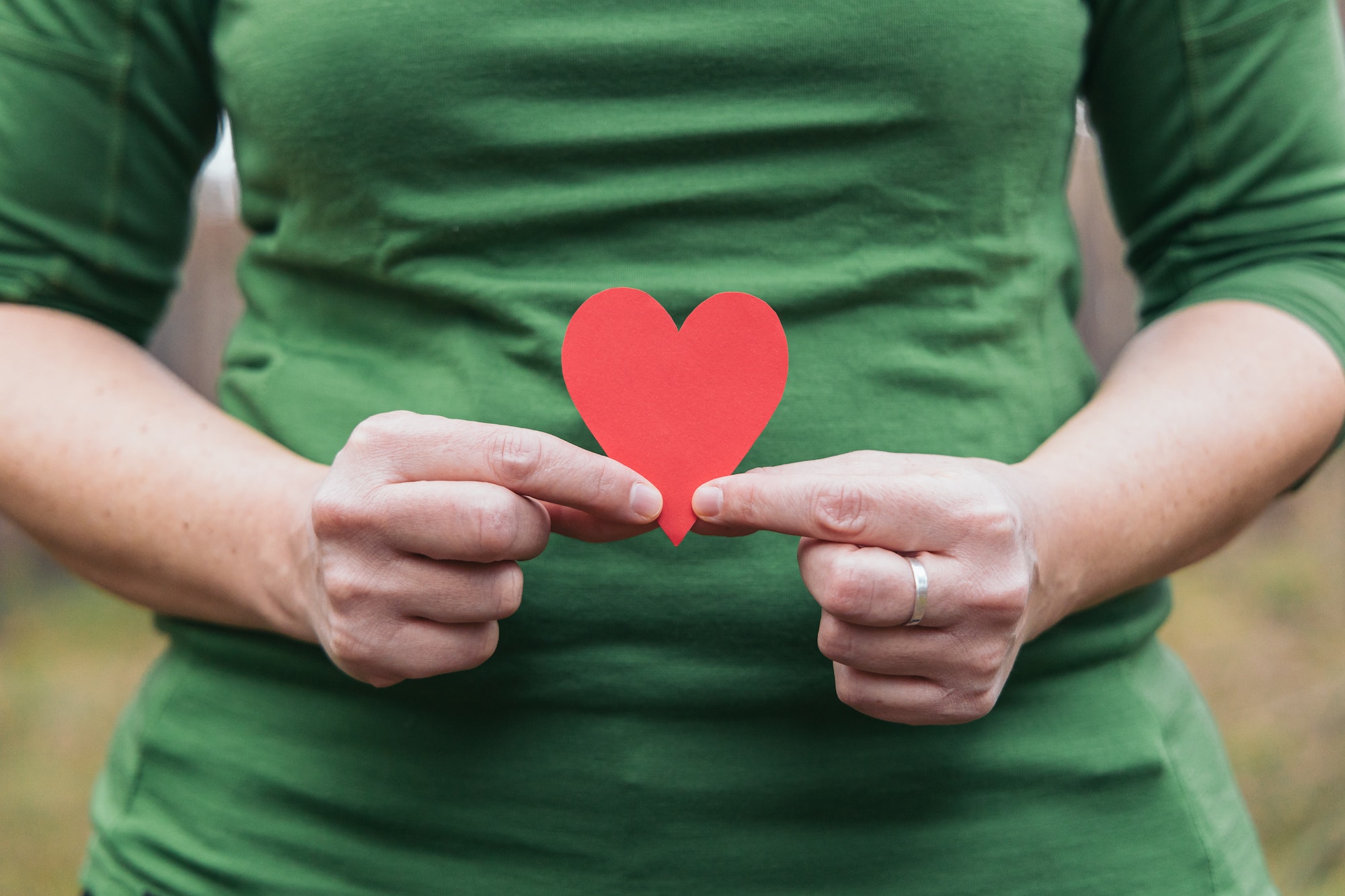 Woman in green T-shirt holding a red heart